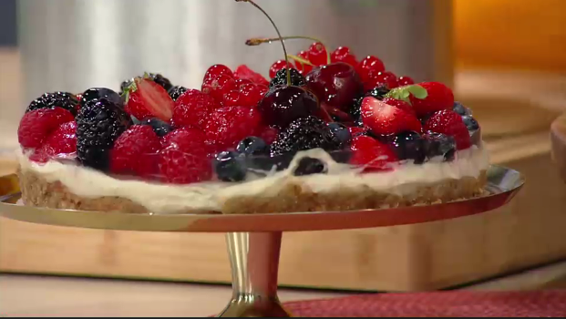 eine üppig mit Beerenobst bedeckte Torte auf einer Tortenplatte