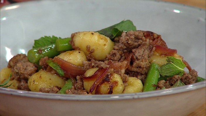 Gnocchi mit Hackfleisch, Zwiebeln, Bohnen und Feigen auf einem Teller