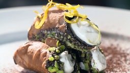Drei Canneloni mit Füllung und Pistazienkruste liegen übereinander.