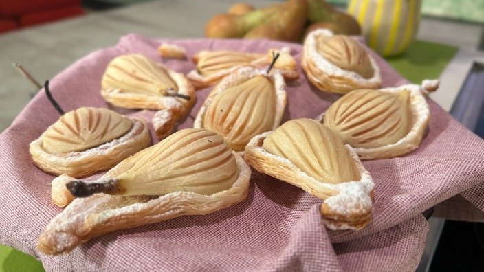 Birnenförmiger Blätterteig. Darauf eingeschnitte, bepuderte Birnenhälften.