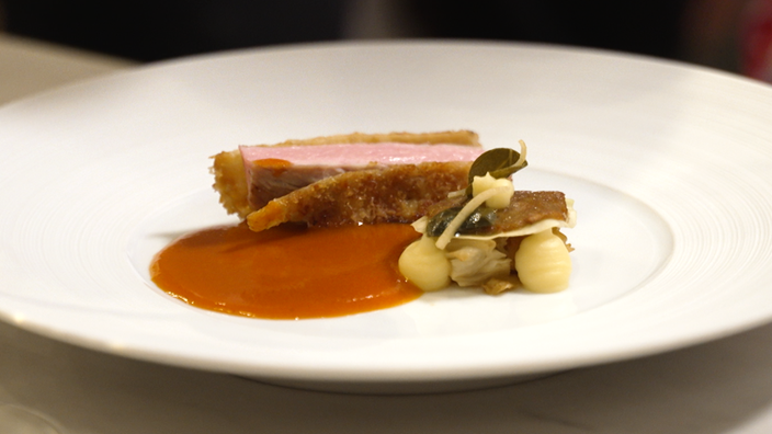 Ein Stück Tafelspitz mit brauner Kruste, daneben ein brauner Klecks Sohne und etwas Beilage.